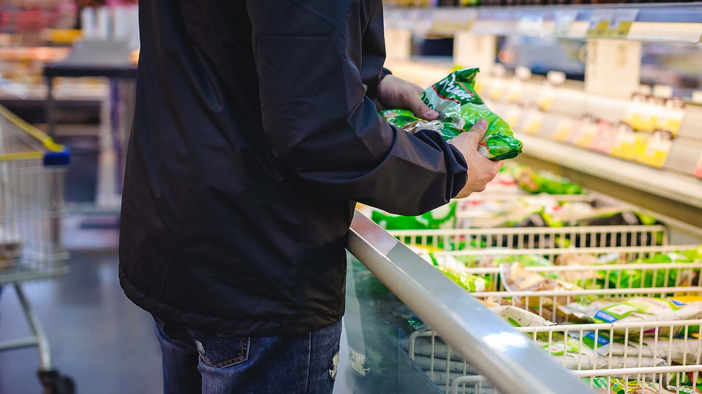 man selects frozen vegetables from supermarket freezer