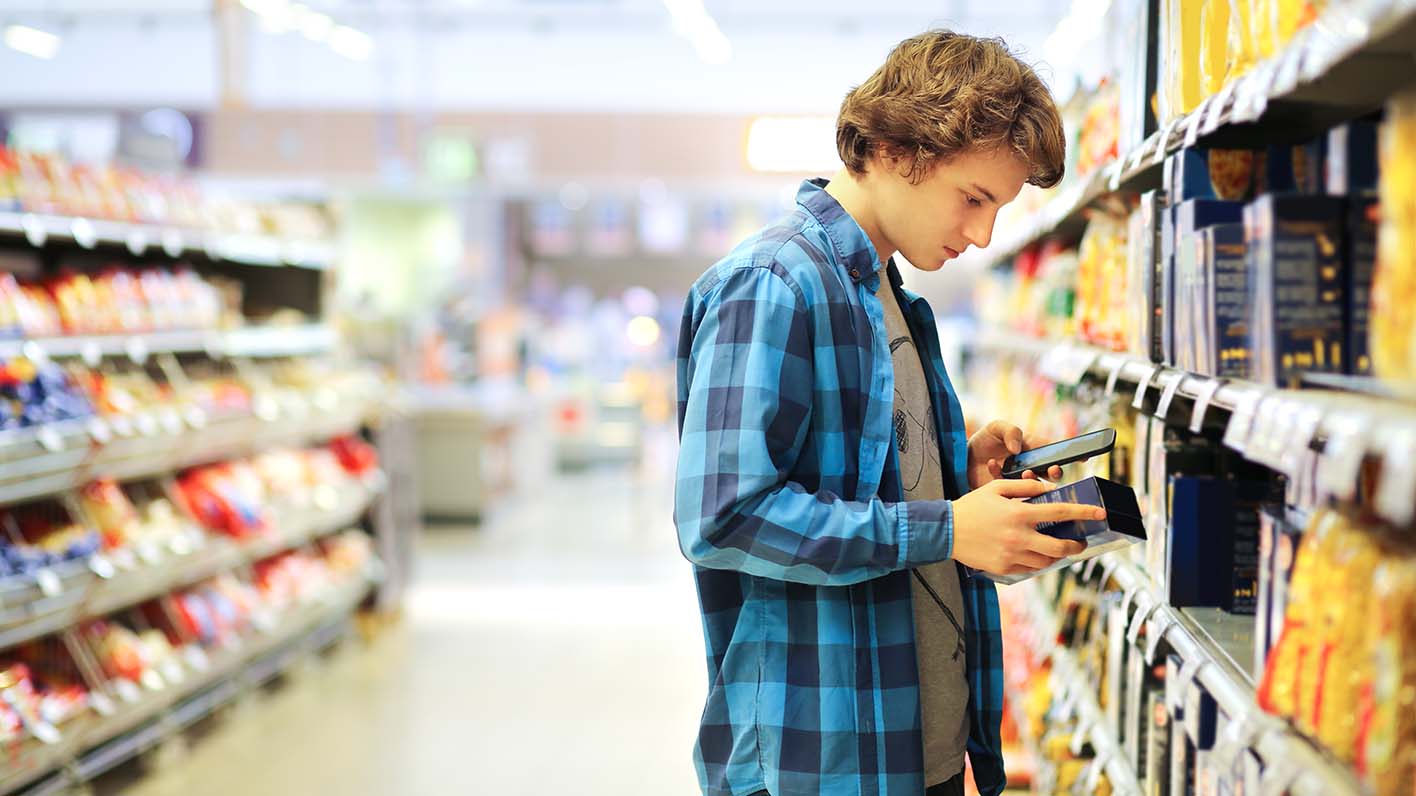 Man shopping in supermarket reading product information
