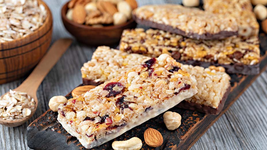 Granola bars with nuts and dried fruits on wooden board.