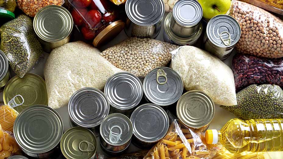 Range of raw cereals, grains, pasta and canned food on a table