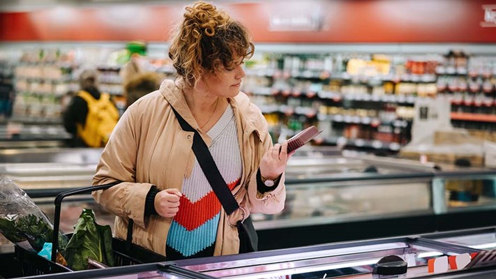 Woman at grocery store reading food labels