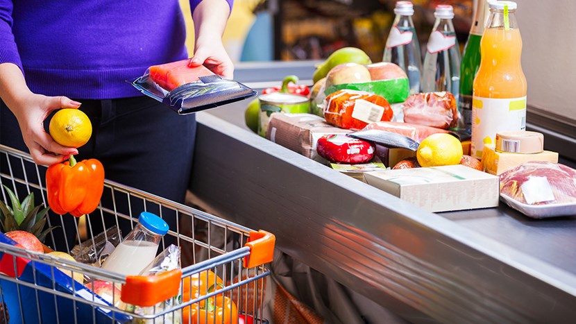 Young woman putting goods on counter in supermarket