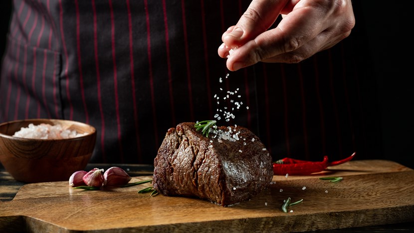 Chef cooking steak adding salt and pepper