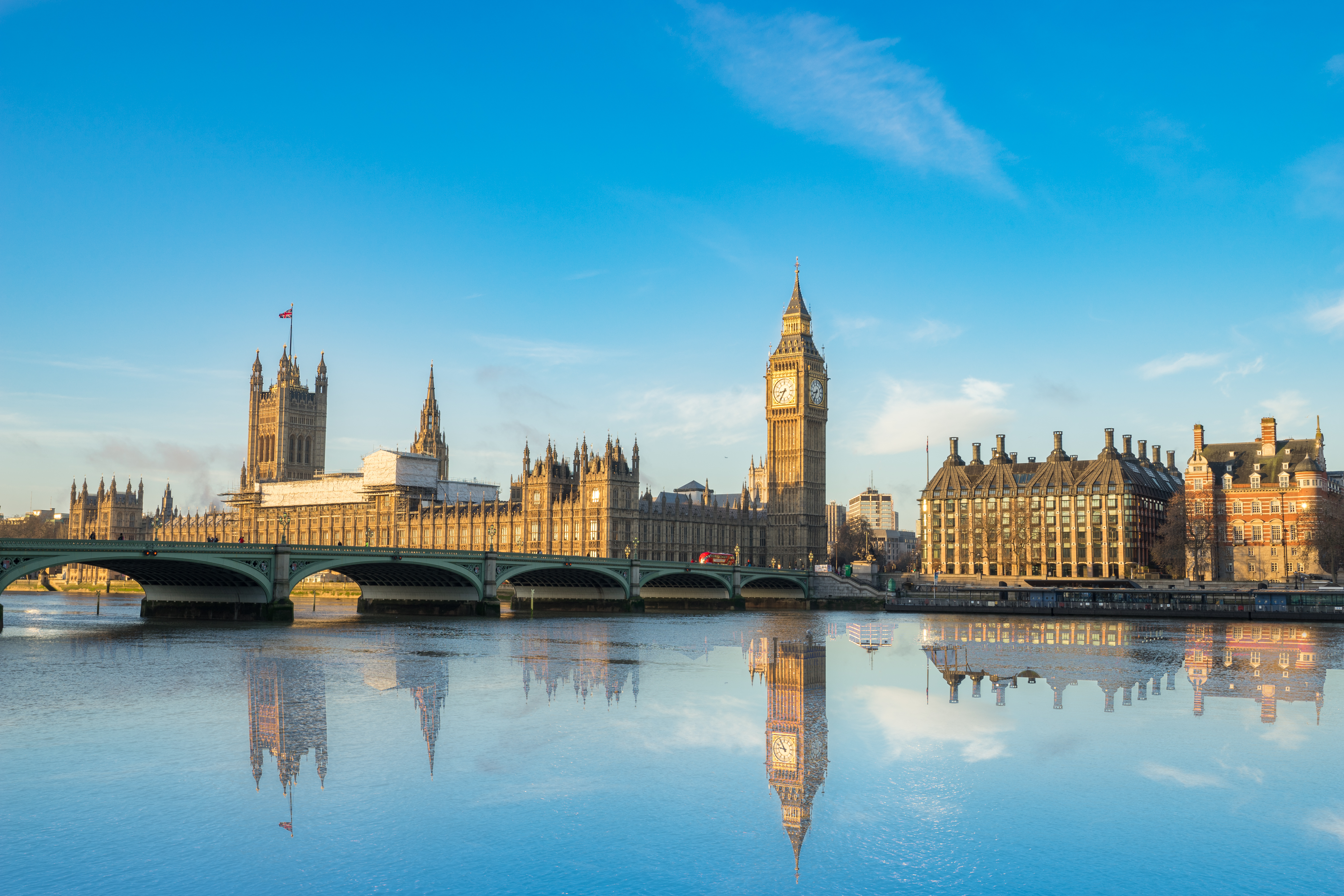 Big Ben and Westminster parliament with colorful sky and water reflection