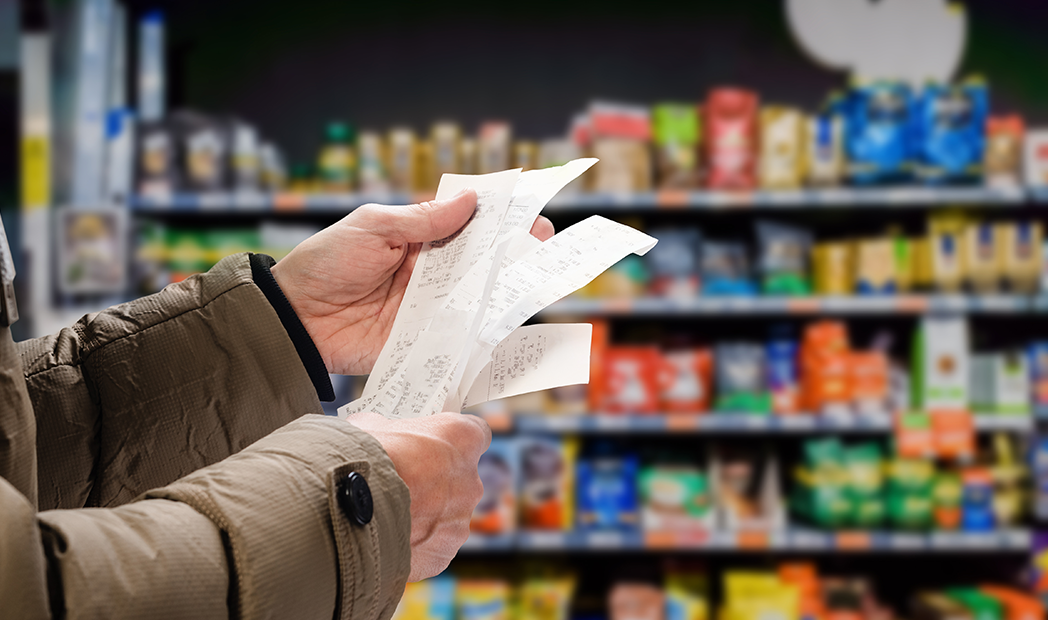 man viewing receipts in supermarket and tracking prices