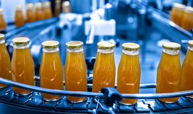 Factory interior of beverage, Production line of manufacturing and packaging juice products, Close up, Glass bottles with screw caps standing on a conveyor belt