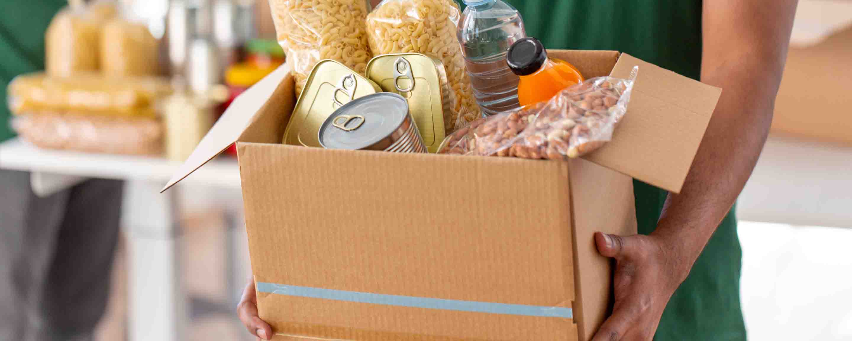 charity volunteer's hands holding box with food