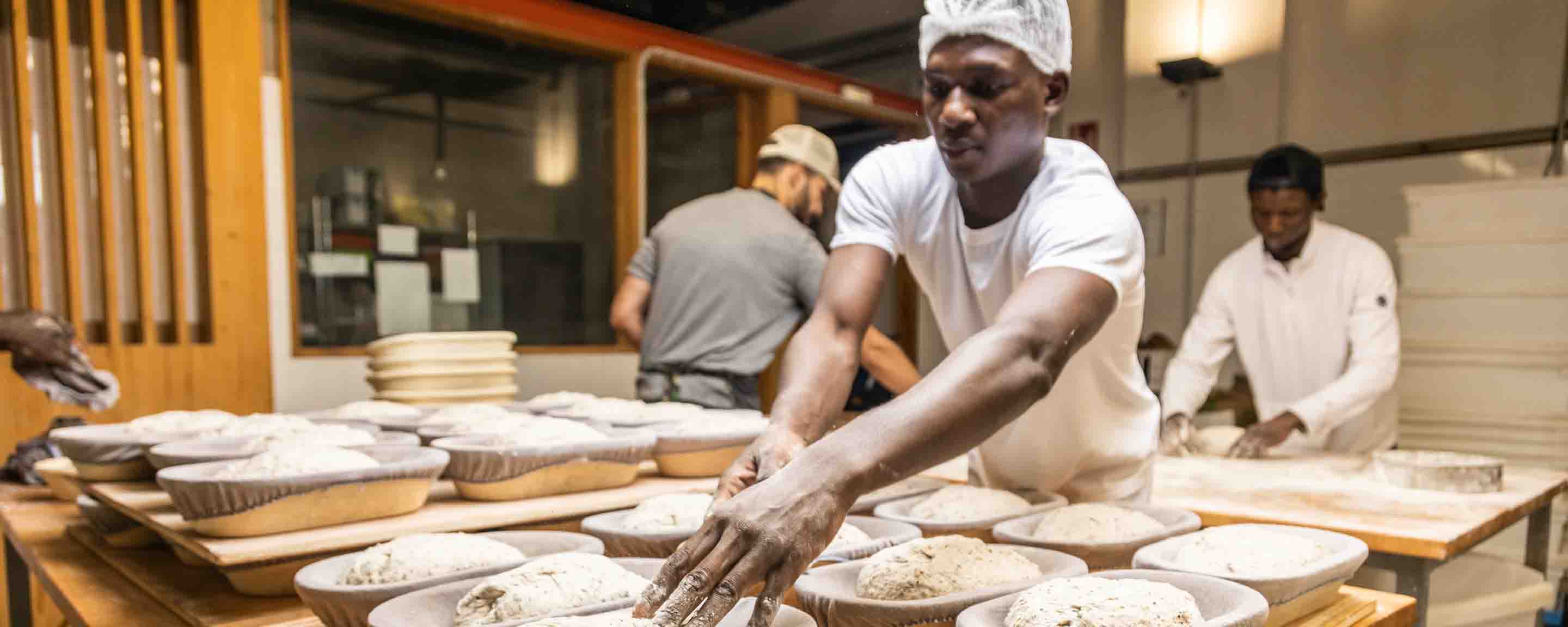 bakers working in a bread factory teaching apprentices