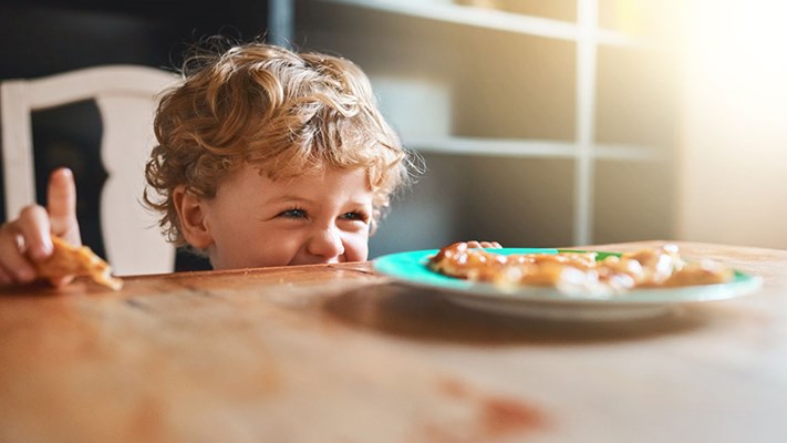 Happy hungry child with lunch at table