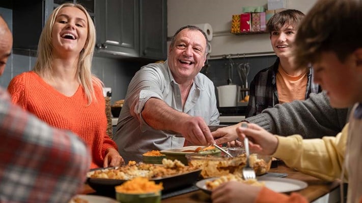 family having a meal together round a dining table in their kitchen
