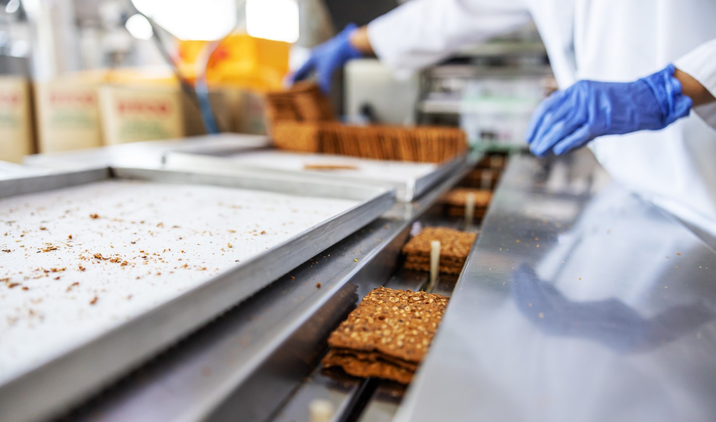 worker picking biscuits form machine standing in food factory