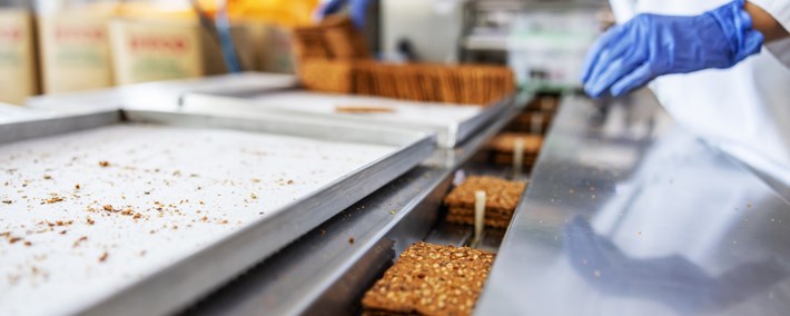 worker picking biscuits form machine standing in food factory