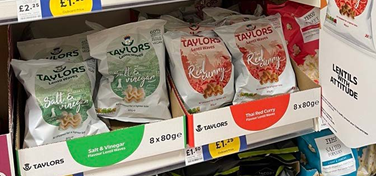 Lentil chips in a rustic wood bowl next to a pile of lentil chips on bamboo matt