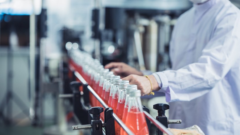 hygiene worker checking glass bottled juice on production line