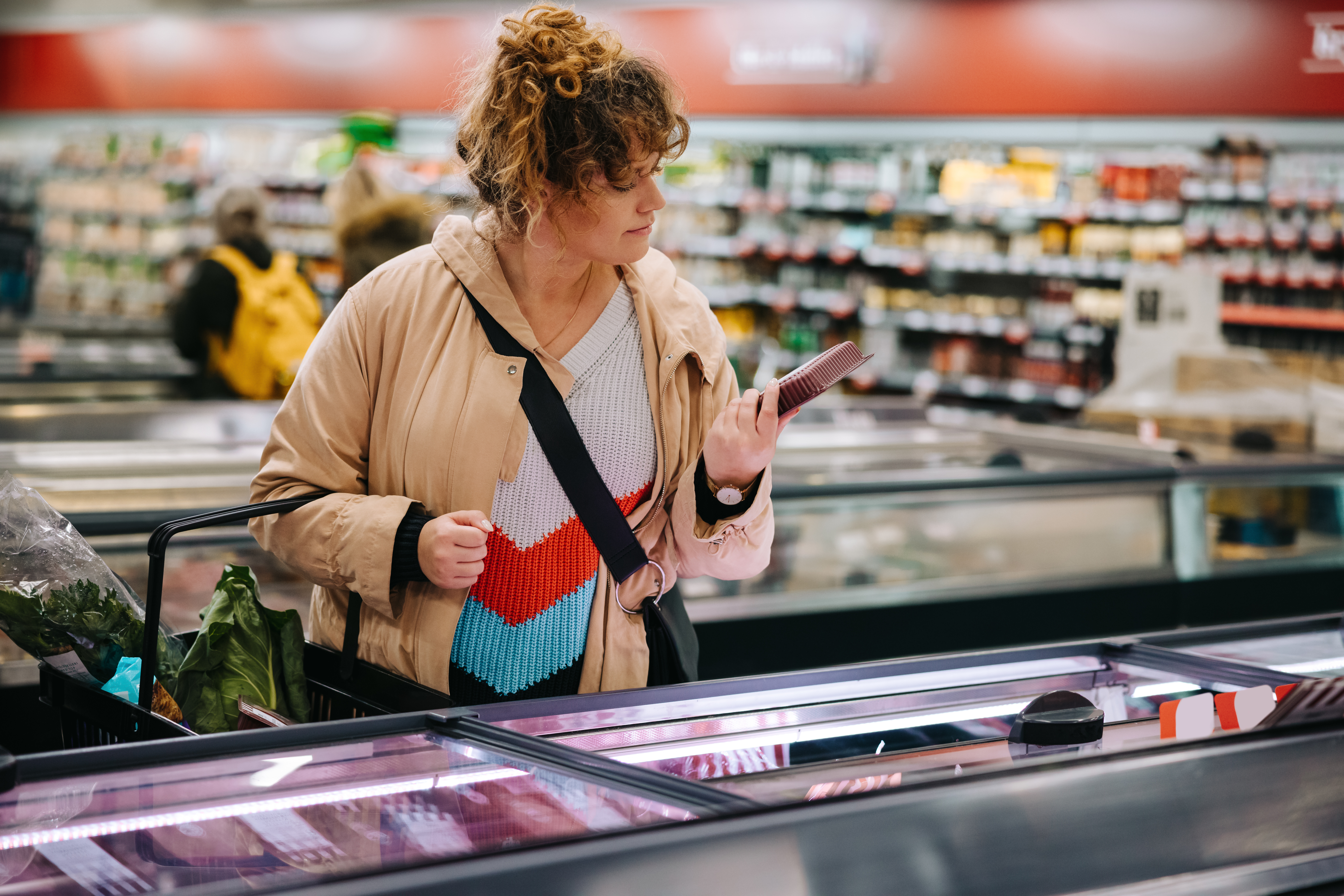 Woman at grocery store reading food labels at supermarket.