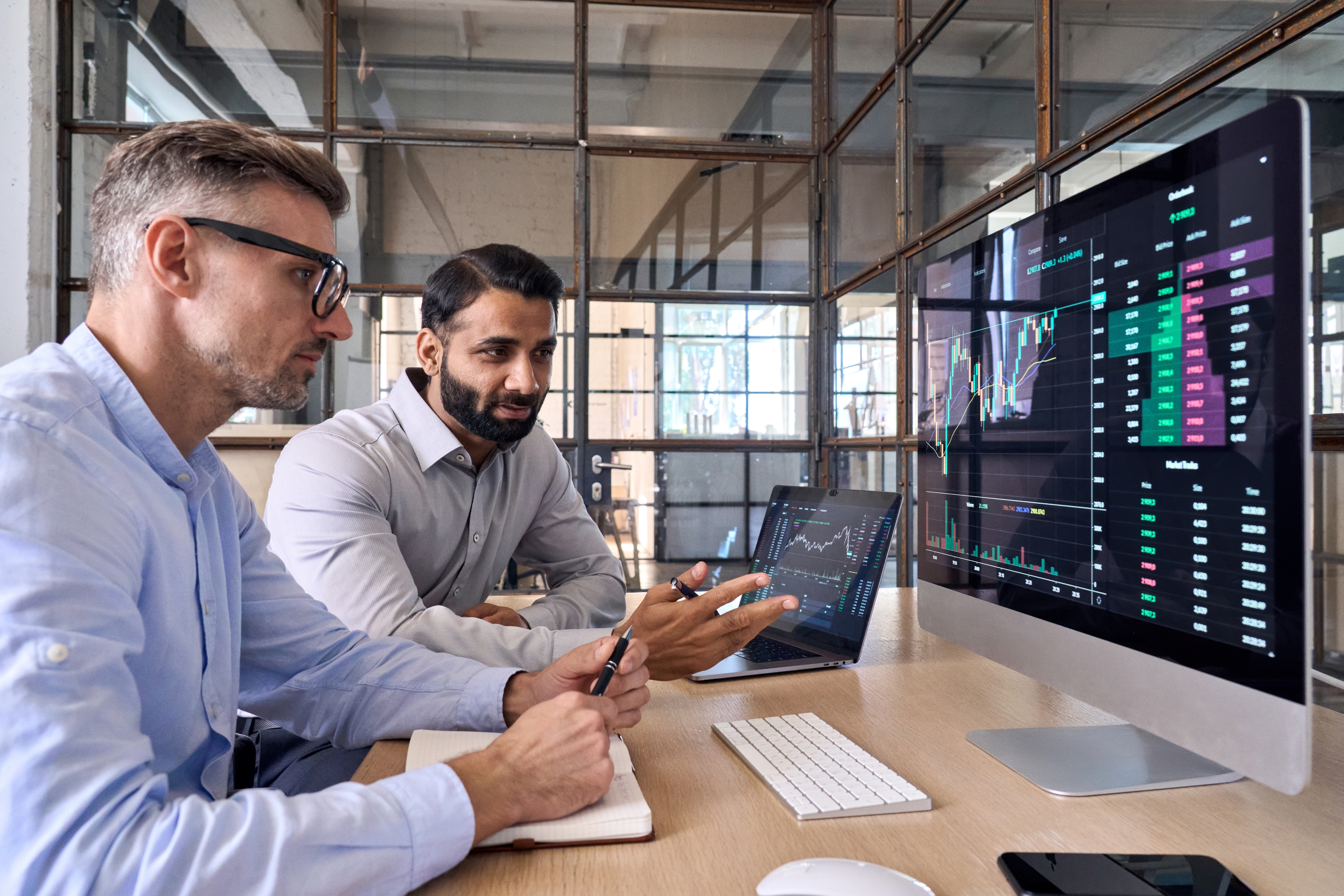 Two colleagues looking at screen analysing stock exchange market