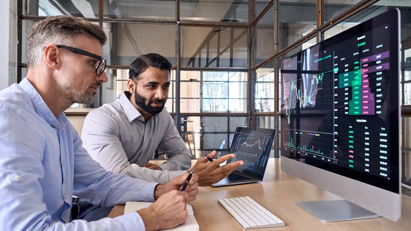 Two colleagues looking at screen analysing stock exchange market
